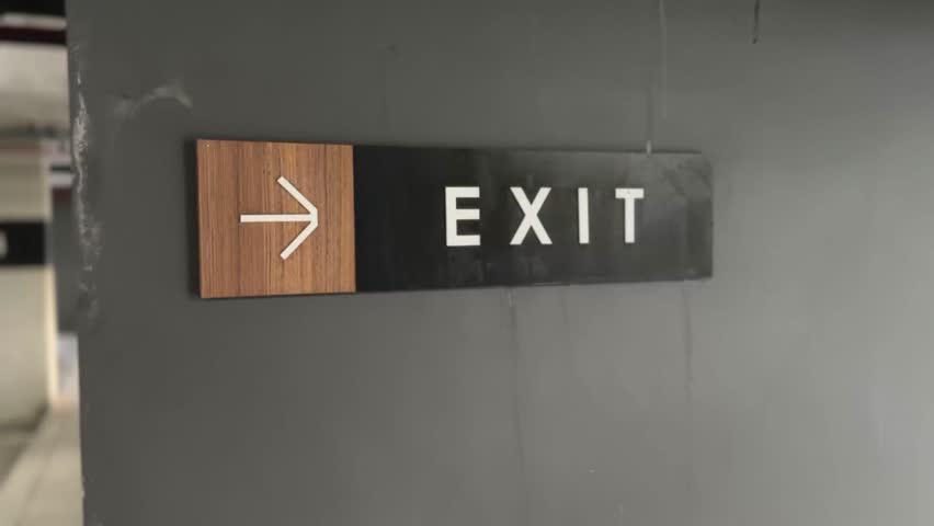 Close-up of “Exit” sign with arrow, offering bold typography and clear directional guidance in public space.