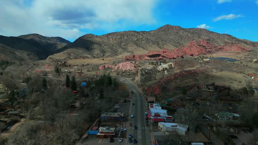 Winter downtown Main Street Morrison Colorado aerial drone Red Rocks Park and Amphitheater Mount Morrison Bear Creek sunny blue sky cloudy shaded traffic car driving backwards motion