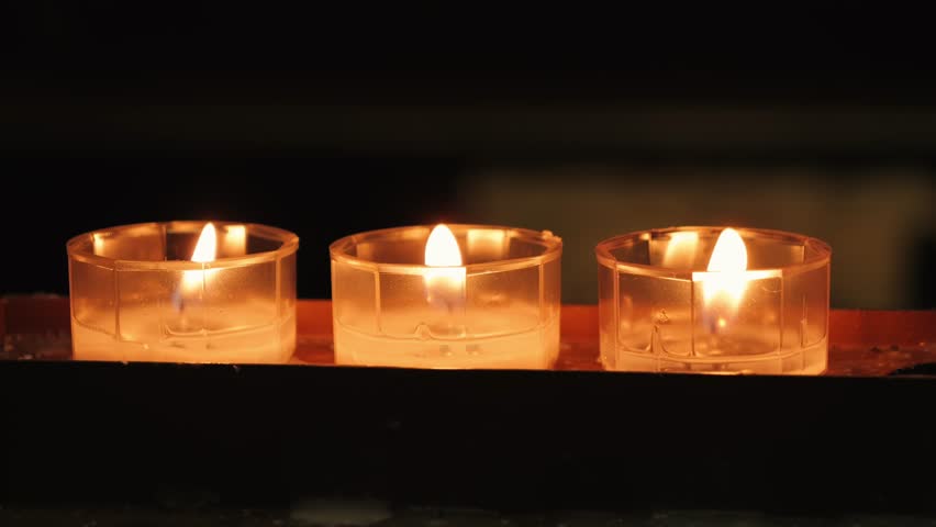 Candles illuminate the interior of church, creating a serene atmosphere with warm, flickering light that reflects the spiritual ambiance and relaxation. High quality 4k footage