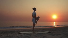 A woman practicing yoga in a standing extended hand to big toe pose (Utthita Hasta Padangusthasana) on a beach at sunset. Concept of balance, strength, flexibility, and mindfulness in nature. - Powered by Shutterstock - Get 15% off with code: PIKWIZARD15