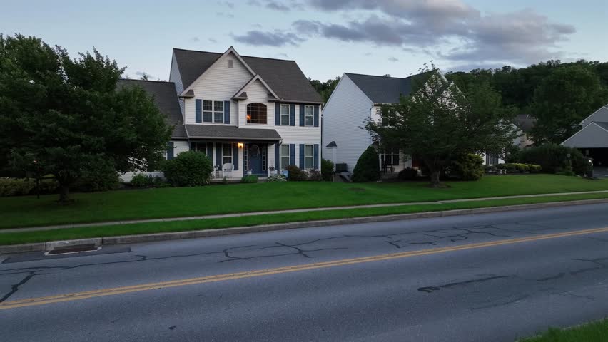 Colonial or craftsman single family house in suburb of American town. Aerial view. Dusk scene with green Grass in front yard. Pennsylvanian village, USA.