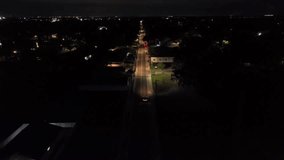 Thunderstorm lightning on night sky of Florida. Suburb district with Main street and driving car. Lighting lantern and streetlights in quiet Suburbia. Aerial following wide shot. FL,USA. - Powered by Shutterstock - Get 15% off with code: PIKWIZARD15