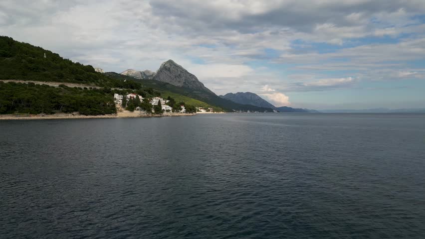 Aerial view of the beautiful Drvenik coastline, where white buildings meet the deep blue sea against a backdrop of green hills, Drvenik, Split-Dalmatia County, Croatia.