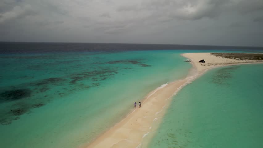 Experience the stunning aerial views of Cayo de Agua beach, where people enjoy the sun and surf. Los Roques Venezuela