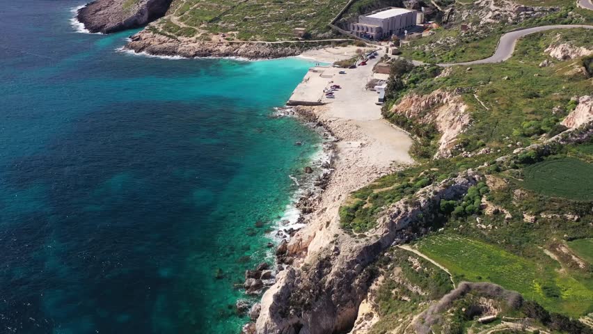 Aerial view of Hondoq ir-Rummien beach, where the turquoise sea meets the rugged coastline and a concrete pier, Gozo Island, Gozo, Malta.