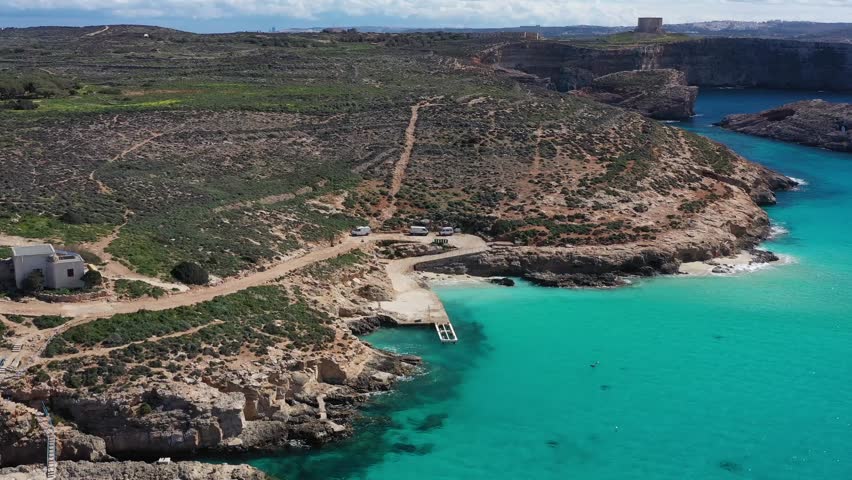 Aerial view of the stunning Blue Lagoon, where turquoise waters meet the rocky coastline, complemented by sparse vegetation, Gozo Island, Gozo, Malta.