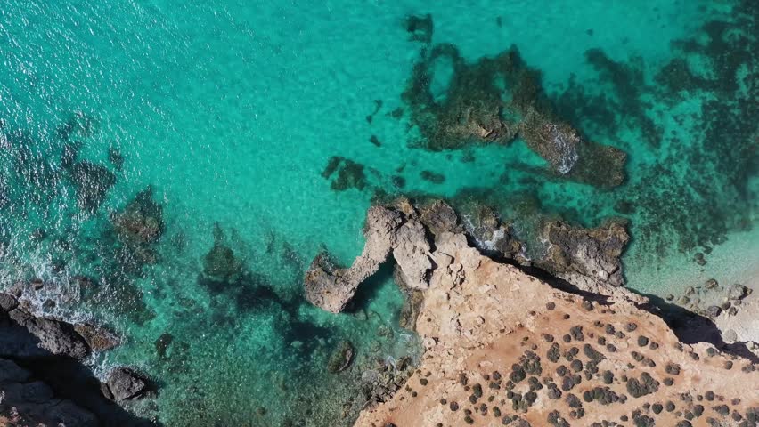 Aerial view of the rugged coastline where the arid land meets the vibrant turquoise sea, creating a beautiful contrast of colors and textures, Gozo Island, Gozo, Malta.