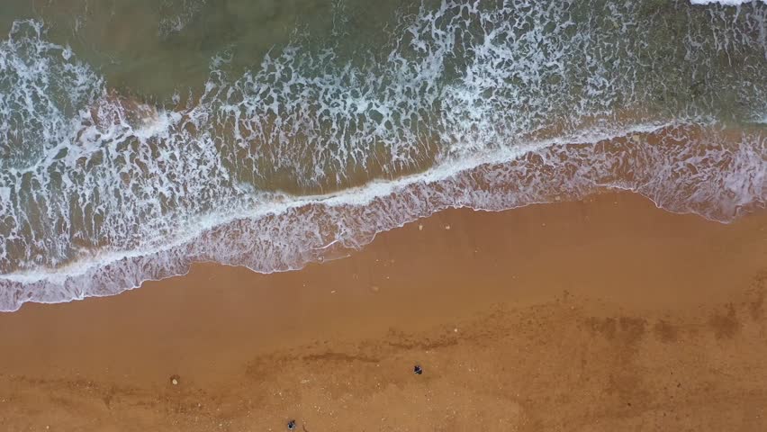 Aerial view of the foamy turquoise sea meeting the sandy beach creating a mesmerizing contrast of textures and tones, Gozo Island, Gozo, Malta.