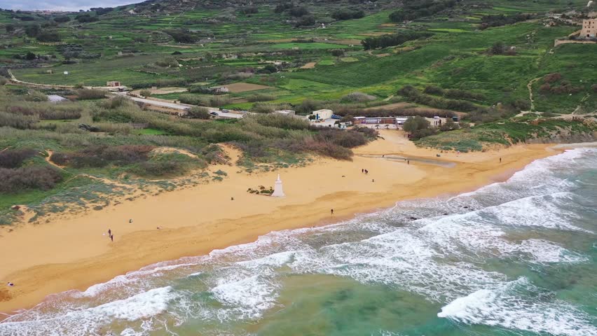 Aerial view of the sandy shores of Ramla Bay where the white statue stands in contrast to the blue water and the green vegetation, Gozo Island, Gozo, Malta.