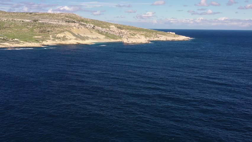 Aerial view of the rugged coastline where the land meets the deep blue sea, creating a stunning contrast of textures and tones, Gozo Island, Gozo, Malta.