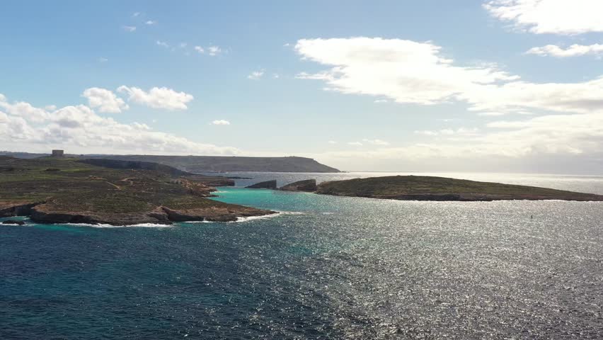 Aerial view of the Blue Lagoon's turquoise waters contrasting against the rugged coastline and the vast expanse of the sea, Gozo Island, Gozo, Malta.