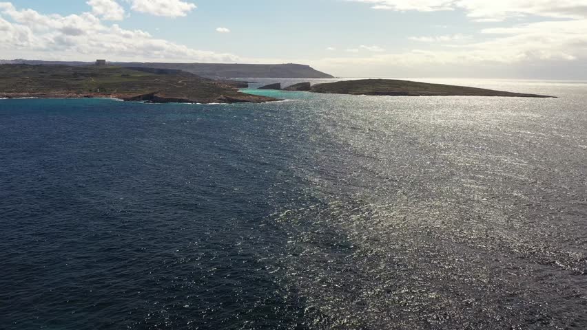 Aerial view of the rugged coastline meeting the turquoise waters, a stark contrast to the darker hues of the deep sea, Gozo Island, Gozo, Malta.