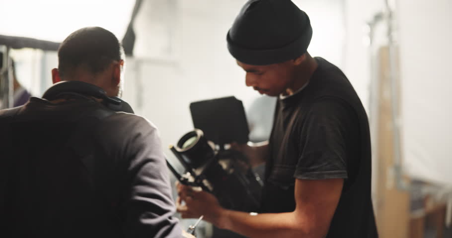Film, setup and men with camera on set for shooting, check lighting and equipment settings. Cinematography, behind the scenes and people in studio for videography, media production and filmmaking