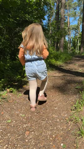A 4-year-old girl walking freely and carefully alone in a forest trail on a sunny summer day. Capturing the spirit of childhood adventure, outdoor play, and connection with nature.