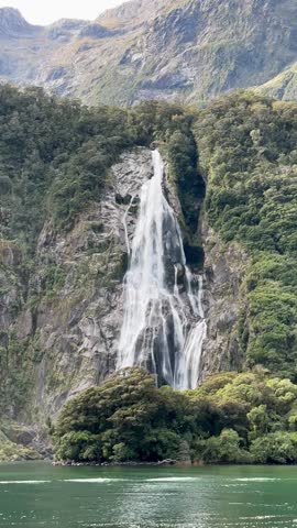  Picturesque view of the waterfall from the water. Cruise on a boat in Milford Sound, New Zealand.