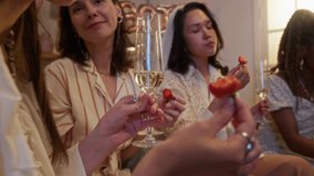 Close up of unrecognizable woman holding glass of champagne and strawberry while singing with her friends during celebrating of bachelorette party - Powered by Shutterstock - Get 15% off with code: PIKWIZARD15