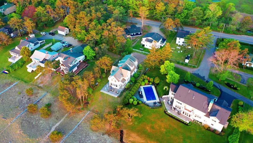 Scenic aerial shot of a beach house in Maine. Prime property on the shore with sandy yard, ocean waves, big windows, and spacious deck. Perfect coastal real estate for vacation or peaceful living.