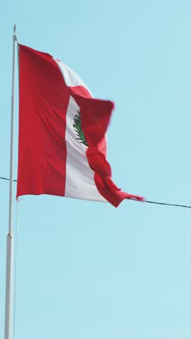 The national flag of peru, with its distinct red and white vertical stripes and coat of arms, flies proudly against a vibrant blue sky