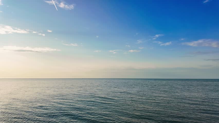 Wide angle seascape of open water under a vast clear blue sky. Time Lapse.
