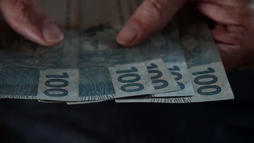 Counting Brazilian money R$100 reais notes. Concept of economy, debts, purchases, trade and payment.