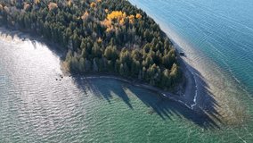 Aerial view of a forested peninsula surrounded by clear blue water with vivid fall foliage and soft morning light - Powered by Shutterstock - Get 15% off with code: PIKWIZARD15