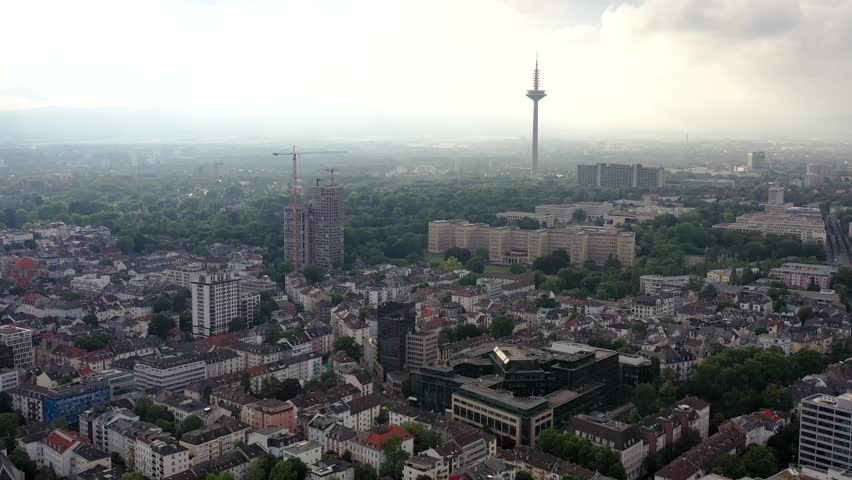 Aerial view of the Frankfurt cityscape, revealing a blend of modern towers and older buildings, all under a soft, muted sky, Frankfurt am Main, Hessen, Germany.