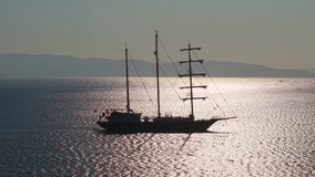 A majestic sailing ship with three masts reflects sunlight on the shimmering Aegean Sea surface - Powered by Shutterstock - Get 15% off with code: PIKWIZARD15