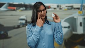 Woman holding bitcoin at airport terminal symbolizes digital currency travel innovation. - Powered by Shutterstock - Get 15% off with code: PIKWIZARD15
