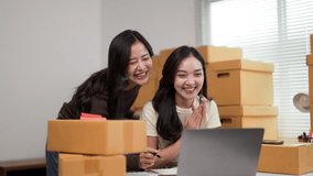 Two happy businesswomen celebrating a successful online sale in their office or storage room, surrounded by cardboard boxes - Powered by Shutterstock - Get 15% off with code: PIKWIZARD15