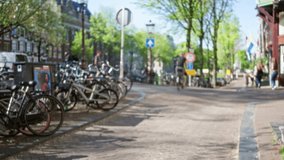 Blurred view of amsterdam canal street with bicycles parked along sidewalk and people walking under clear blue sky, capturing the charm of netherlands urban life in spring. - Powered by Shutterstock - Get 15% off with code: PIKWIZARD15