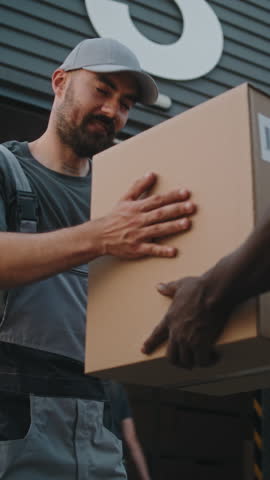 Multiethnic Workers Loading Cardboard Boxes with Online Orders, E-Commerce Goods in Delivery Truck. Outside of Logistics Distribution Warehouse. Work in Delivery Service. Static Shot. Vertical Shot.