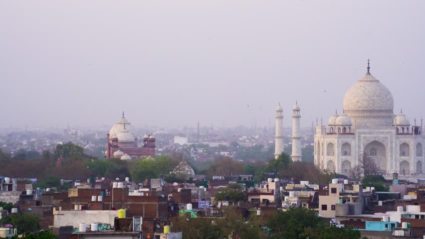 Dusk shot slow pan of birds flying around famous white marble monument landmark Taj Mahal a popular tourist destination in Agra India