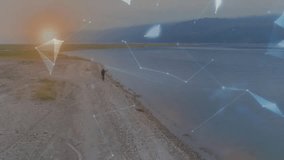 Man walking shoreline triggers animated technology network shapes forming rotating globe above hand. Technology, innovation, connectivity, digital, futuristic, environment, networking - Powered by Shutterstock - Get 15% off with code: PIKWIZARD15
