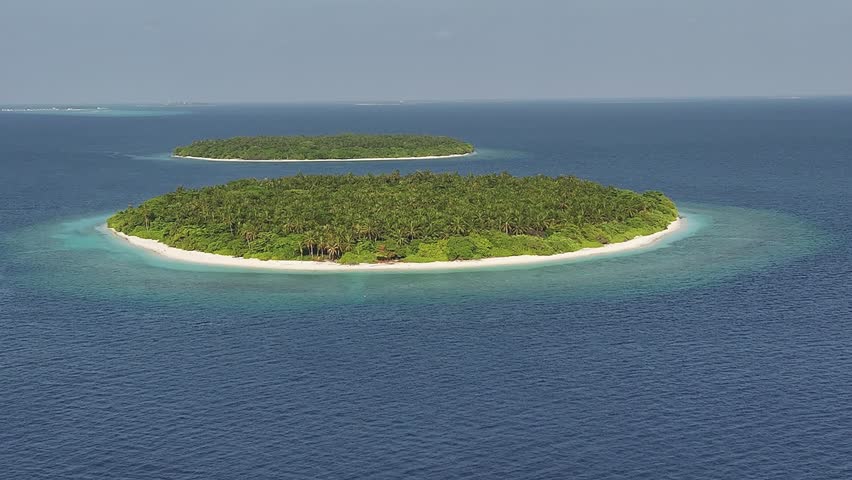 Aerial view of a lush green island encircled by a white sandy beach and clear turquoise water, contrasting with the deep blue sea, Kendhoo, Baa Atoll, Maldives.