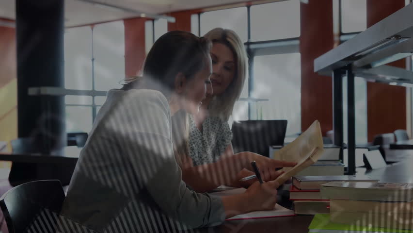 Mentee turning pages and tapping laptop as mentor pointing diagrams for education with data overlay. Collaboration, learning, education, digital, teamwork, knowledge, mentorship