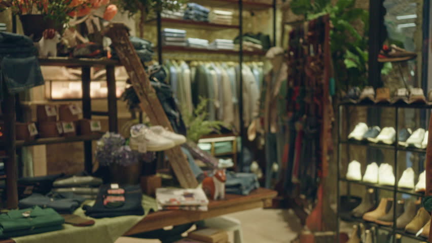 Blurred shop interior featuring clothes, shoes, and accessories with earthy tones and abundant product display.
