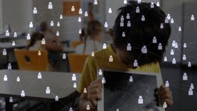 Boy tilting head viewing tablet initiating network icons in classroom illustrating collaboration. Education, technology, collaboration, innovation, youth, digital, learning - Powered by Shutterstock - Get 15% off with code: PIKWIZARD15