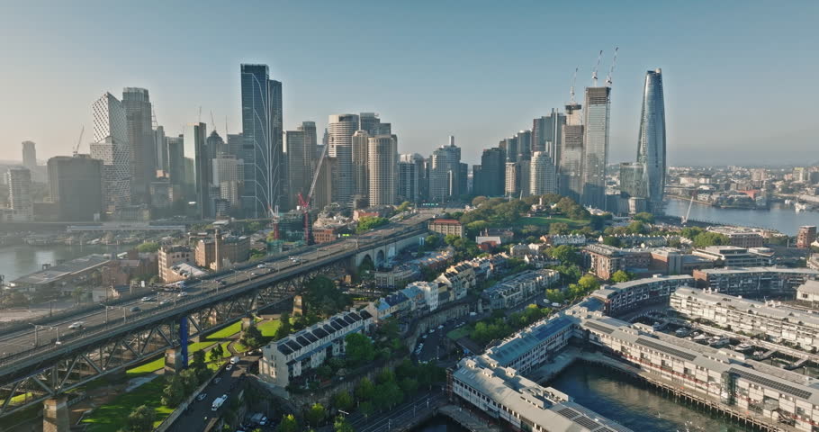 Australia, Sydney: Aerial view Sydney's urban landscape with skyscrapers, bridge road cars, highway traffic, and green spaces reflecting modern city architecture skyline in background. Drone footage