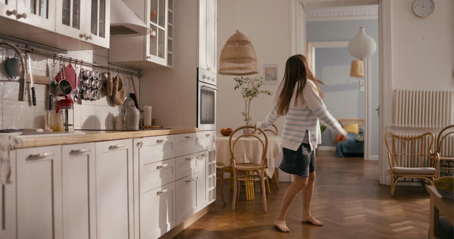Cheerful girl improvises and dances during a day off at home on the floor barefoot in a modern cozy apartment. Fun day off
