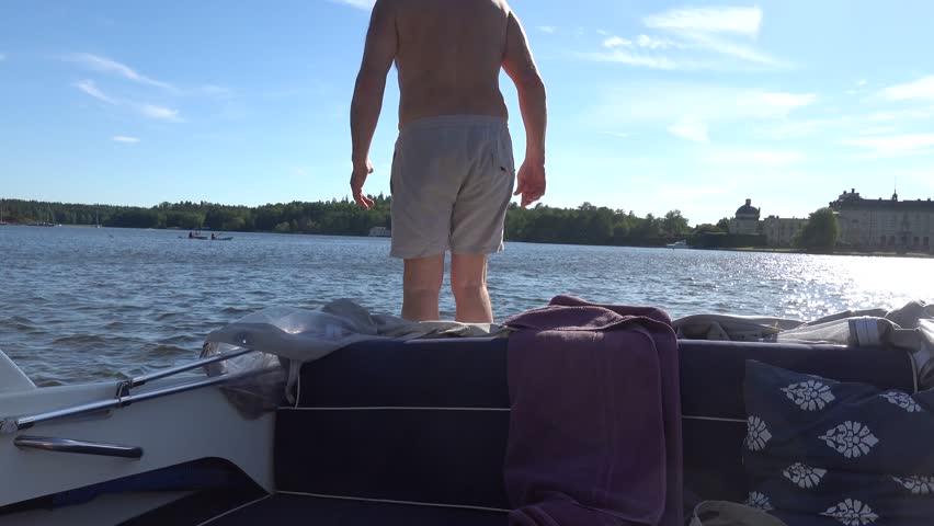 Stockholm, Sweden A man jumps into Lake Malaren from a small motorboat in summer. 