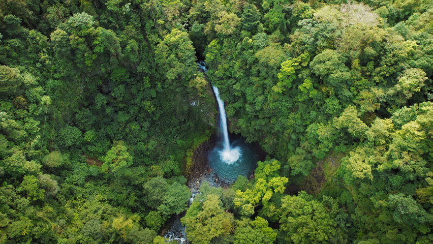 Aerial view of tall waterfall La Fortuna plunging into a pool in lush rainforest of Costa Rica