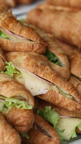 Multiple croissants with ham, cheese, and greens filling served on plates