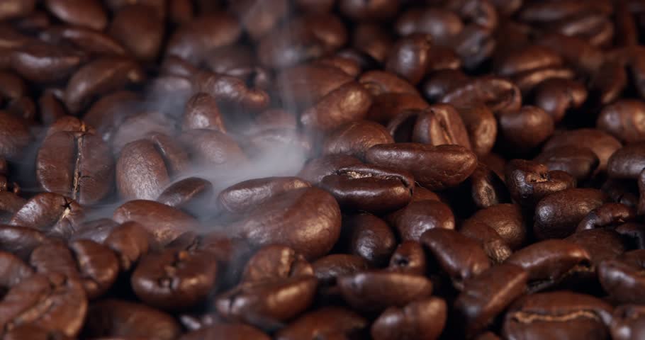 Close up of seeds of coffee. Fragrant coffee beans are roasted smoke comes from coffee beans.