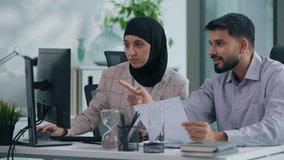 Two Islamic Arabian Muslim business team colleagues celebrate online pc success at office table businesswoman in hijab with businessman happy amazed computer work achievement victory high five gesture - Powered by Shutterstock - Get 15% off with code: PIKWIZARD15