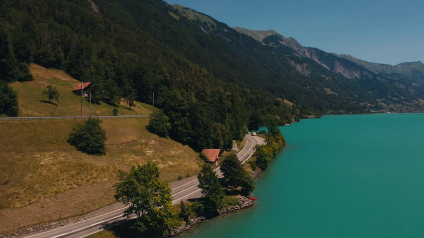 aerial top view drone incredibly colored lake Brienz in Switzerland near mountains hills serpentine road. summer background of blue sky lake Brienzersee mountains in Switzerland. Turquoise Azure Water