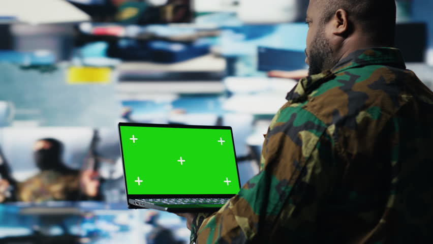 African american trooper holding laptop with copy space screen in a control tower, using modern digital tools and satellite imagery to ensure a successful national defense matter. Camera B.