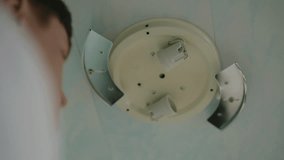 Close-up low-angle view of unrecognizable man in gloves replacing light bulb in ceiling light fixture at home. Concept of electricity maintenance, proper illumination and electrical safety. - Powered by Shutterstock - Get 15% off with code: PIKWIZARD15