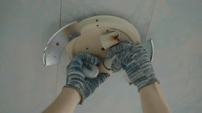 Close-up of professional electrician wearing protective gloves replacing ceiling light bulb in living room. Concept of electricity maintenance, proper illumination and electrical safety, slow motion. - Powered by Shutterstock - Get 15% off with code: PIKWIZARD15