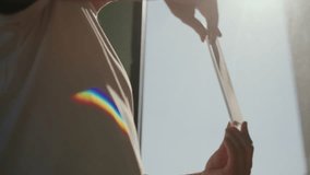 Low-angle view of scientist holding and spinning rectangular glass prism, revealing light refraction and generating colorful rainbow spectrum, close-up. Concept physics principles of refraction. - Powered by Shutterstock - Get 15% off with code: PIKWIZARD15