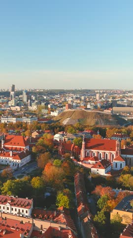 Beautiful vertical aerial Vilnius city Old town panorama in autumn with orange and yellow foliage. Aerial sunny evening view. Fall city scenery in Vilnius, Lithuania